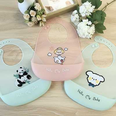 Bavoir silicone ornés de petits dessins, posés sur une table en bois