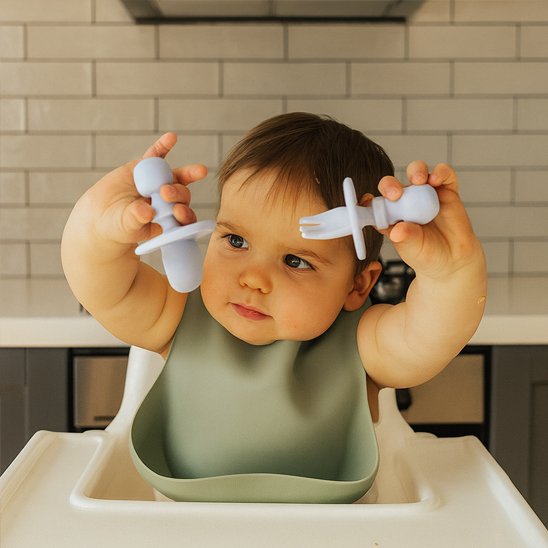 Couvert bébé​ bleu ciel, bébé tient fièrement ses deux couverts 